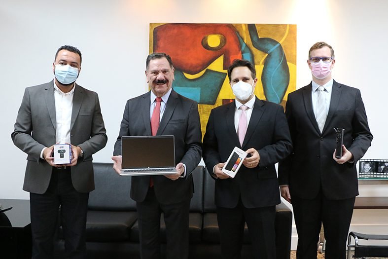 Grupo de autoridades do judiciário capixaba posa para foto segurando aparelhos de informática.